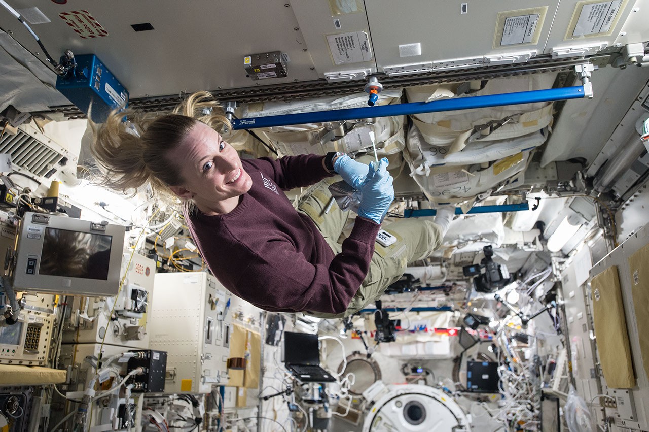 Astronauta trabaja dentro de la Estación Espacial Internacional mientras toma muestras de microbios.